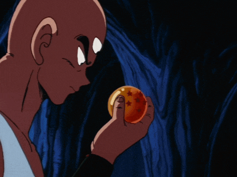 a bald man is holding a dragon ball in his right hand