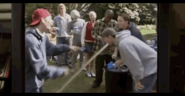 a group of people are playing a game with a bucket and a rope