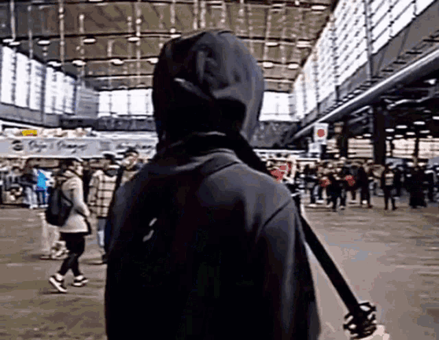 a person in a black hoodie is standing in a crowded area