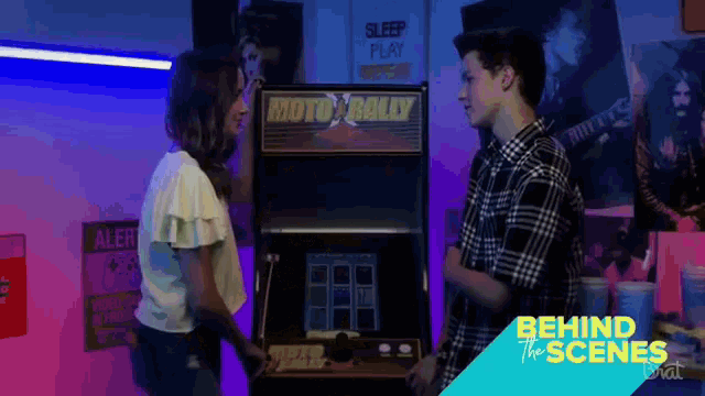 a man and a woman are standing in front of an arcade machine that says moto rally