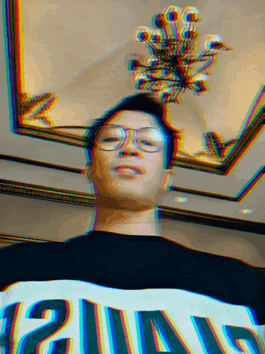 a blurry picture of a man wearing glasses and a shirt that says ' 21a15 ' on it