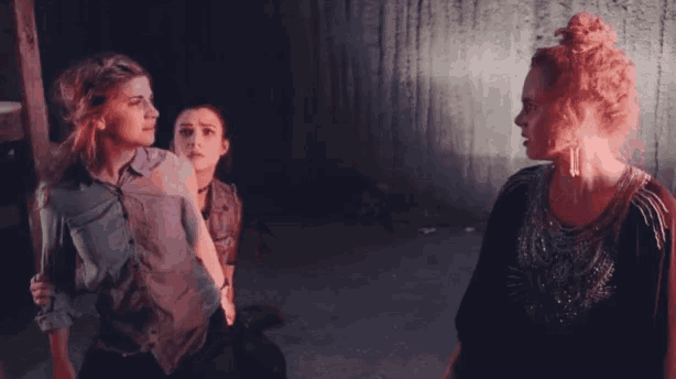 a group of women are standing in a dark room fighting each other