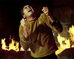 a man in a star trek shirt is screaming in front of flames
