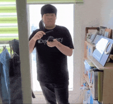 a man wearing a black shirt that says discovery is holding a camera