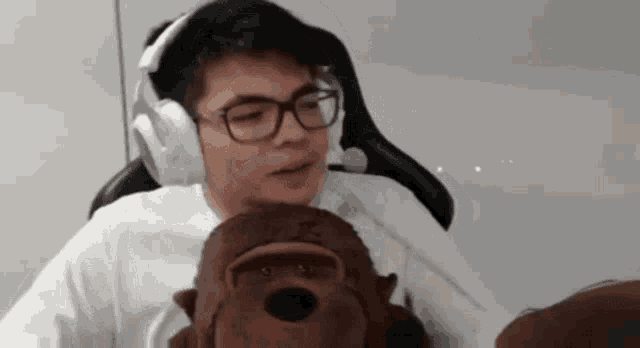 a man wearing headphones is holding a stuffed gorilla .