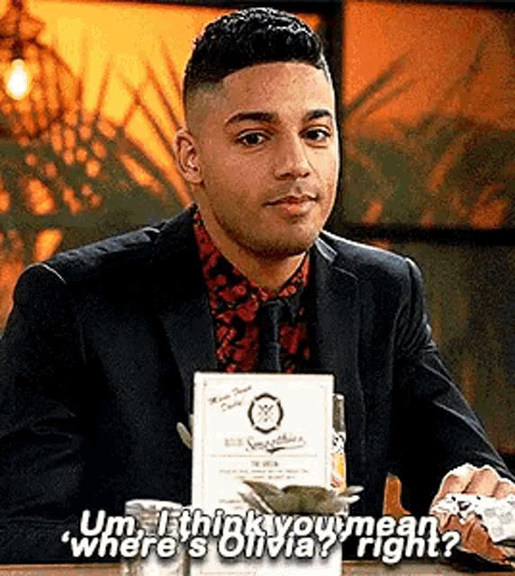 a man in a suit and tie is sitting at a table in a restaurant talking to a woman .