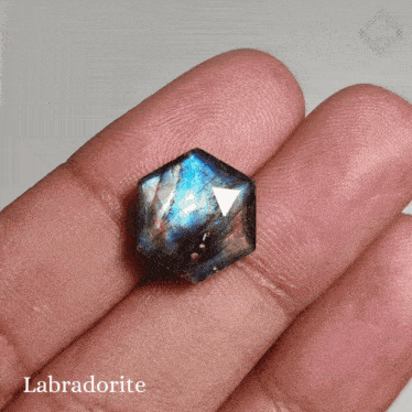 a person is holding a labradorite in their finger