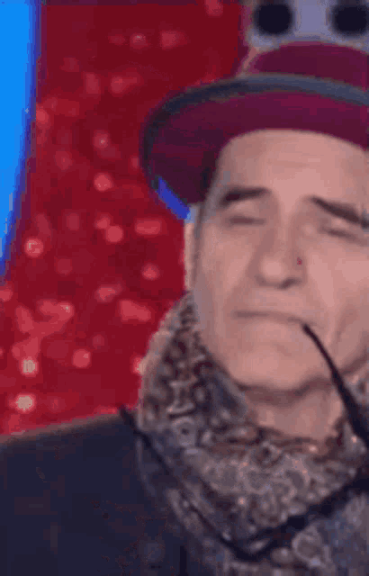 a man wearing a hat and scarf has a snake in his mouth .