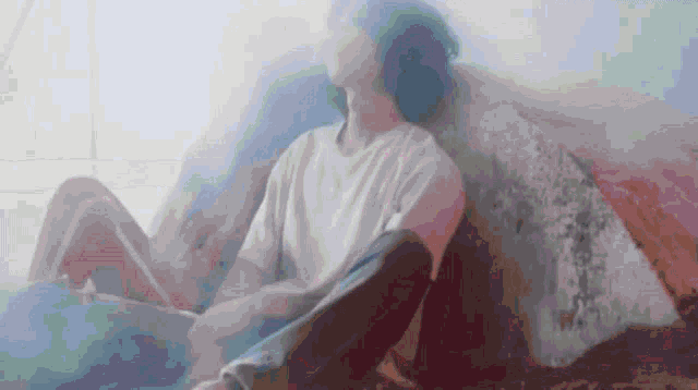 a blurry picture of a person sitting on a couch with their legs crossed