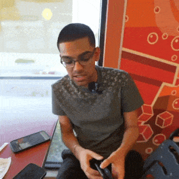 a man wearing glasses and a louis vuitton shirt is looking at his cell phone