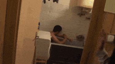 a man is taking a bath in a bathroom with a toilet in the background