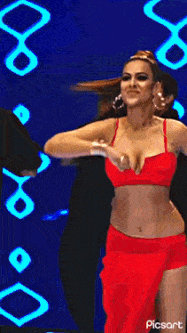 a woman in a red crop top is dancing on a stage .