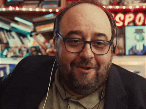 a man with glasses and a beard is smiling in front of a sign that says spooky