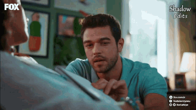 a man in a blue shirt is talking to a woman in a room with fox written on the bottom