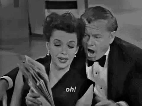 a man and a woman are sitting next to each other and the woman is holding a magazine .