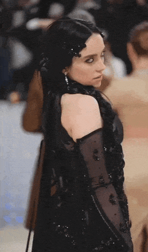 a woman wearing a black dress and gloves looks down