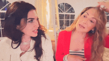two women are standing next to each other in a room