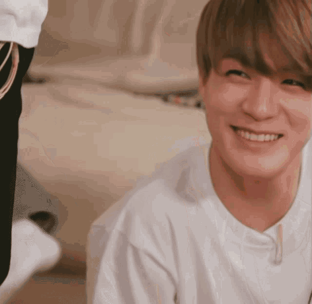 a young man in a white shirt is smiling