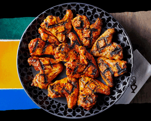 a plate of grilled chicken wings with a napkin that says ' chefs ' on it