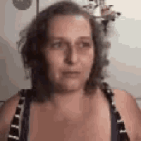 a woman is making a funny face while wearing a blue and black tank top .