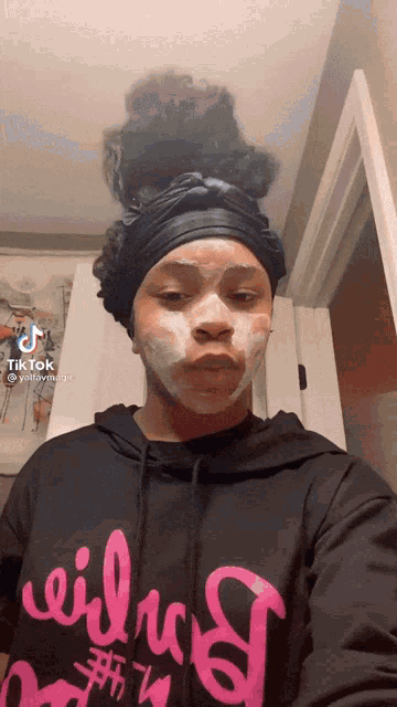 a woman with a mask on her face is wearing a black hoodie with the word wildcats on it