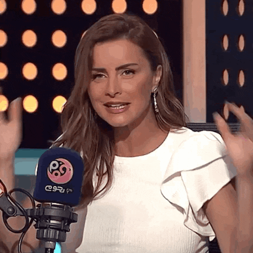 a woman in a white top stands in front of a microphone that says p9