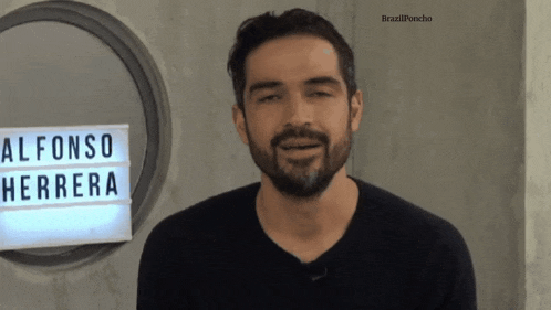 a man stands in front of a sign which says alfonso herrera