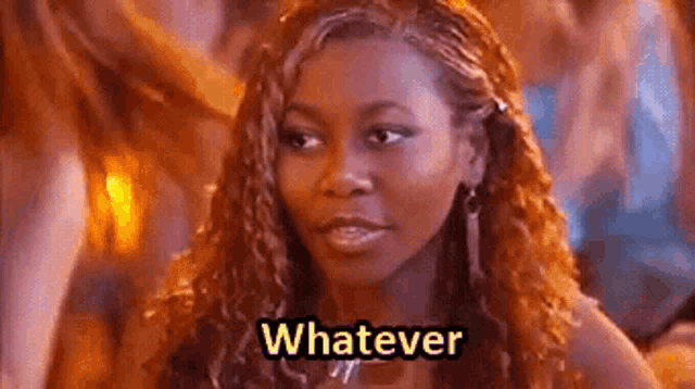 a woman with long red hair is standing in front of a crowd and says `` whatever '' .