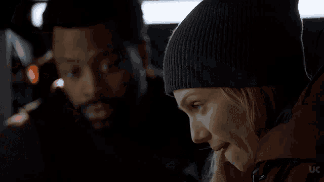 a man and a woman are sitting next to each other in a dark room and looking at each other .