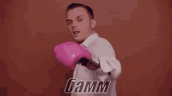 a man wearing pink boxing gloves is standing in front of a red background .