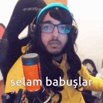 a man wearing glasses and headphones is standing in front of a microphone with the words selam babuslar written on it