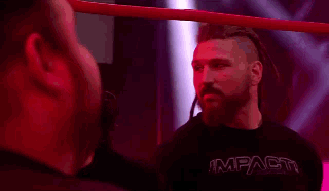 a man with dreadlocks and a beard is standing in a wrestling ring .