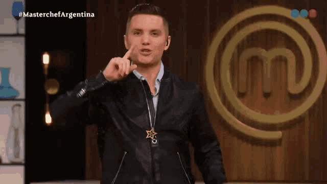 a man stands in front of a master chef argentina logo