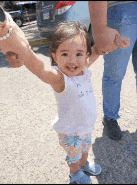 a little girl wearing a cat shirt is holding someone 's hand and smiling