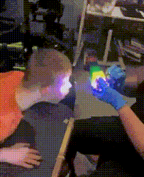 a person wearing blue gloves is holding a rainbow light in front of a child 's face