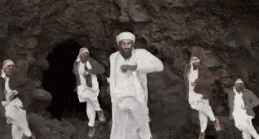 a group of men are dancing in a cave with a man in the middle