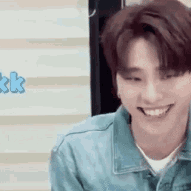 a young man wearing a blue denim jacket is smiling .