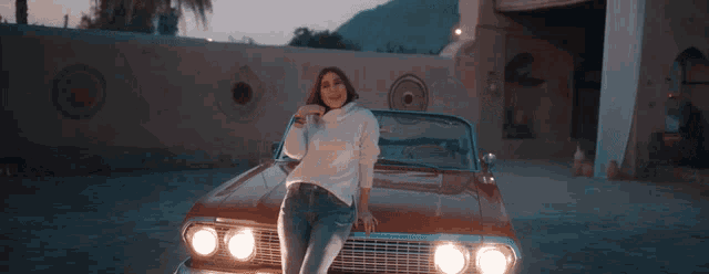 a woman in a white sweater is sitting on a red car