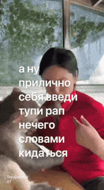 a woman in a red shirt is sitting next to a dog with a caption in russian