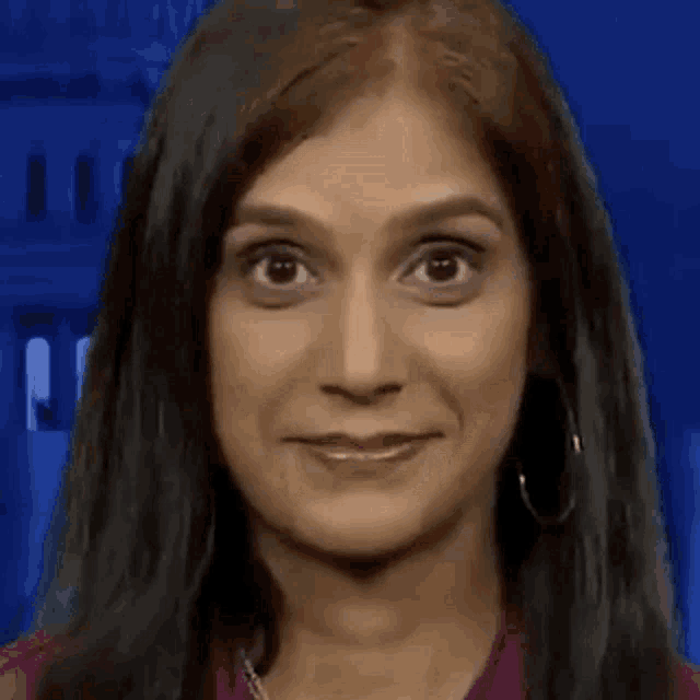 a close up of a woman 's face with a blue background making a funny face .