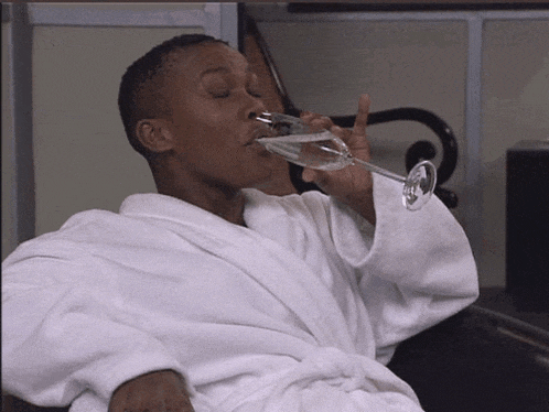 a man in a bathrobe drinks from a glass