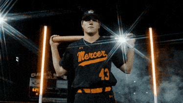 a mercer baseball player is holding a bat on his shoulder