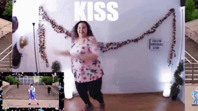 a woman is dancing in front of a wall with the word kiss on it