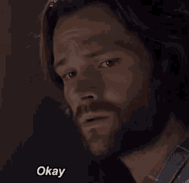 a close up of a man 's face with the words `` okay '' written on the bottom .
