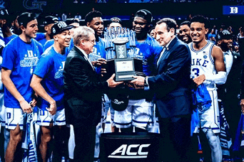 duke men 's basketball team holding a trophy in front of an acc sign