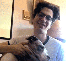 a man with glasses is holding a dog in his arms