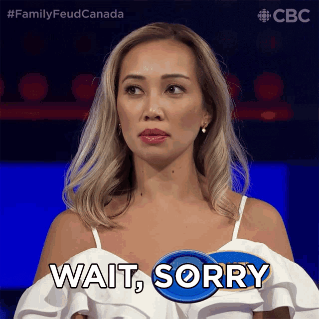 a woman wearing a white top says wait sorry