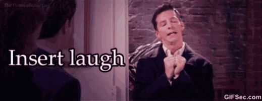 a man in a suit laughs in front of a mirror