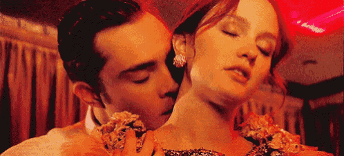 a man is kissing a woman on the neck while she is wearing a dress .