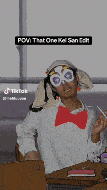 a person wearing a mask and a bow tie is sitting at a desk